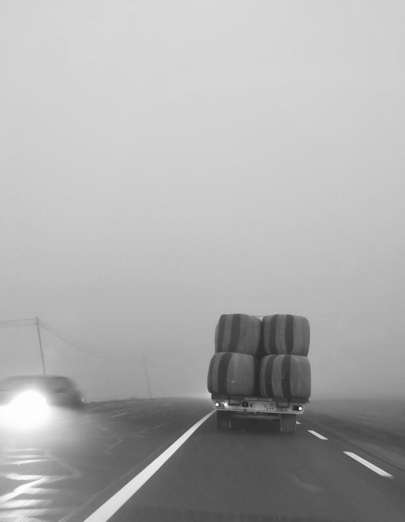 Une remorque agricole chargée de paille sur une route embrumé. 